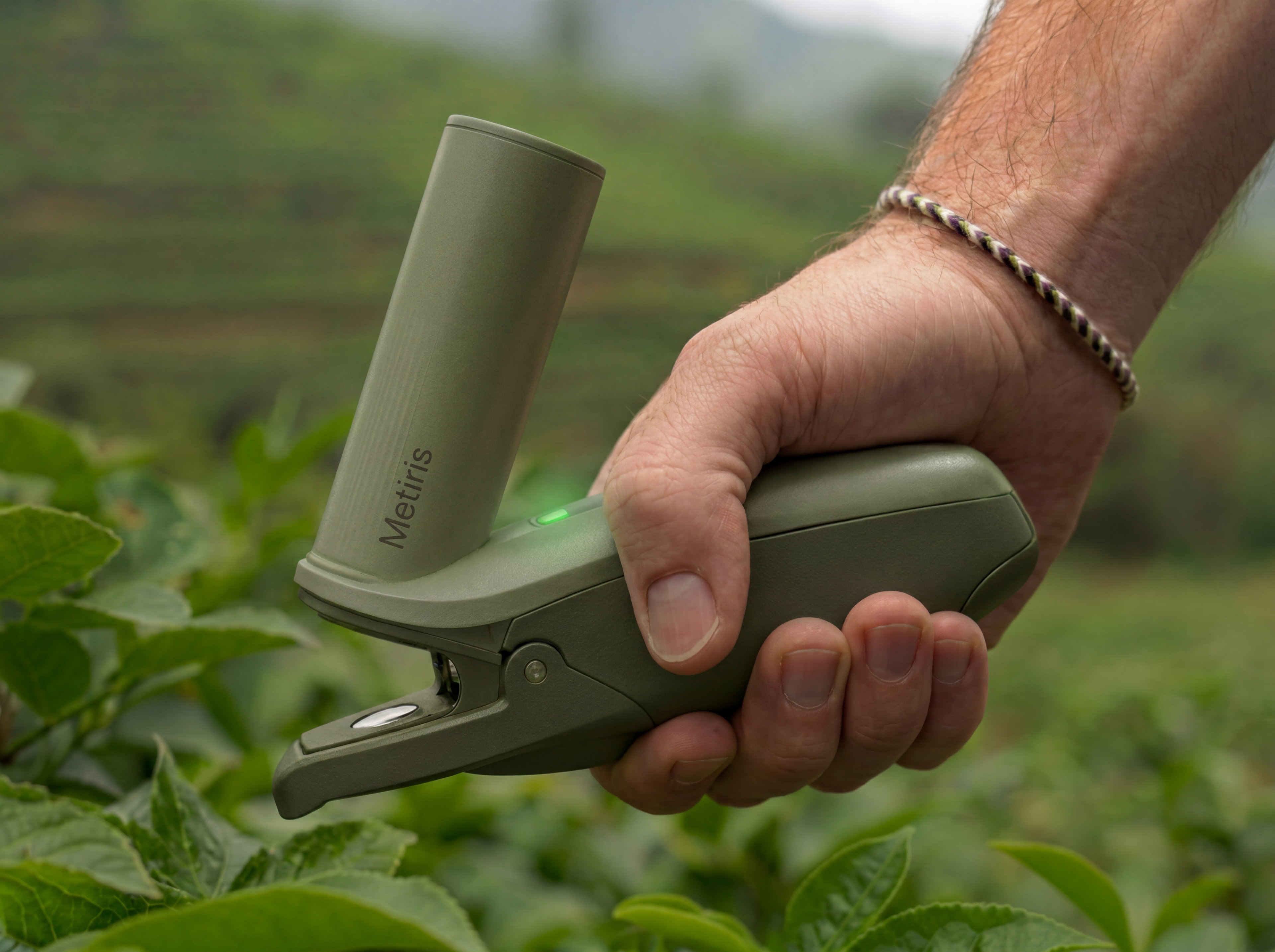 A grower holding the Metiris handheld sensor clipped onto a leaf in the field